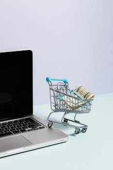 Shopping Cart with Money on Top of a Laptop